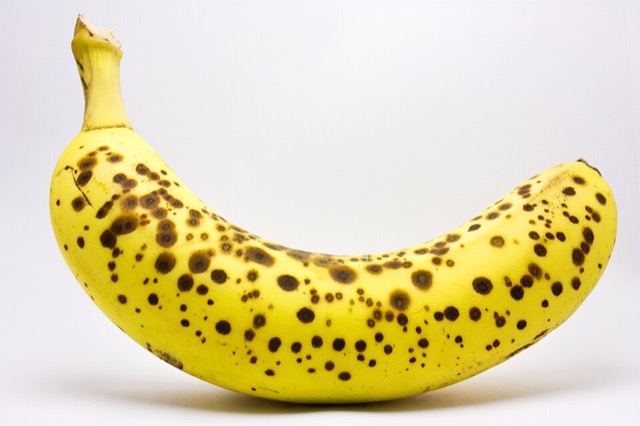 A yellow banana with small brown sugar spots